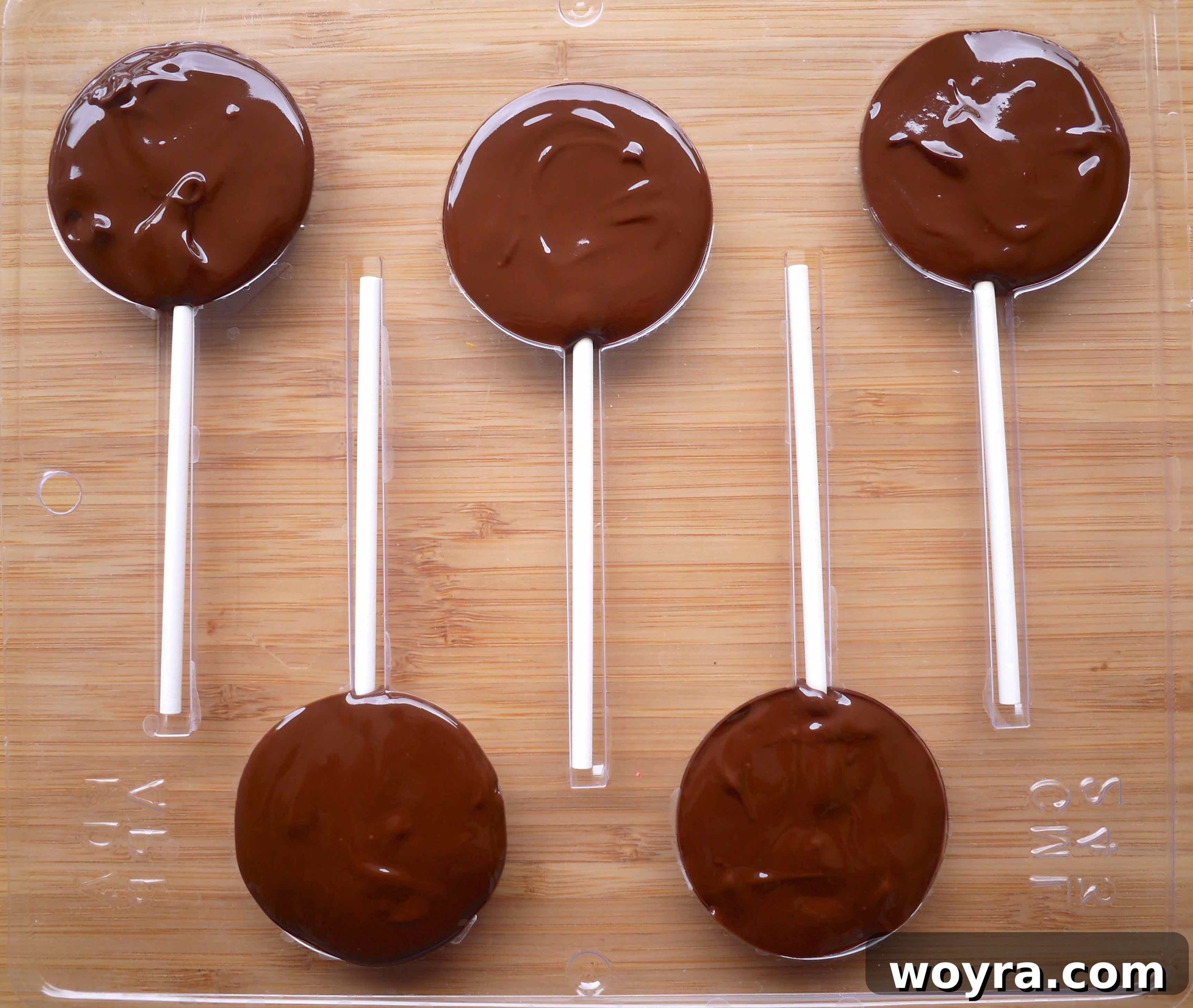 Artisan Chocolate Fruit Pops 6 Melted chocolate neatly fills the lollipop molds, creating an even surface over the toppings and sticks.