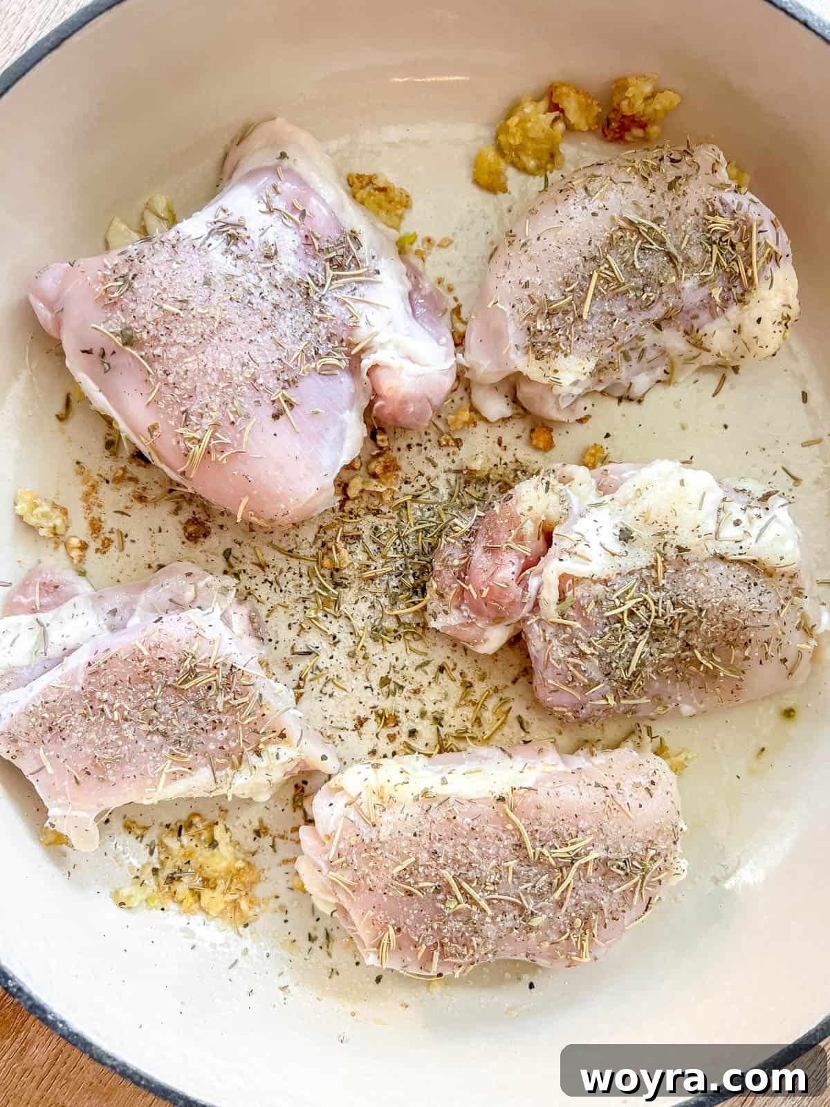 Seasoned chicken thighs placed skin-side down in a Dutch oven with sautéed aromatics.