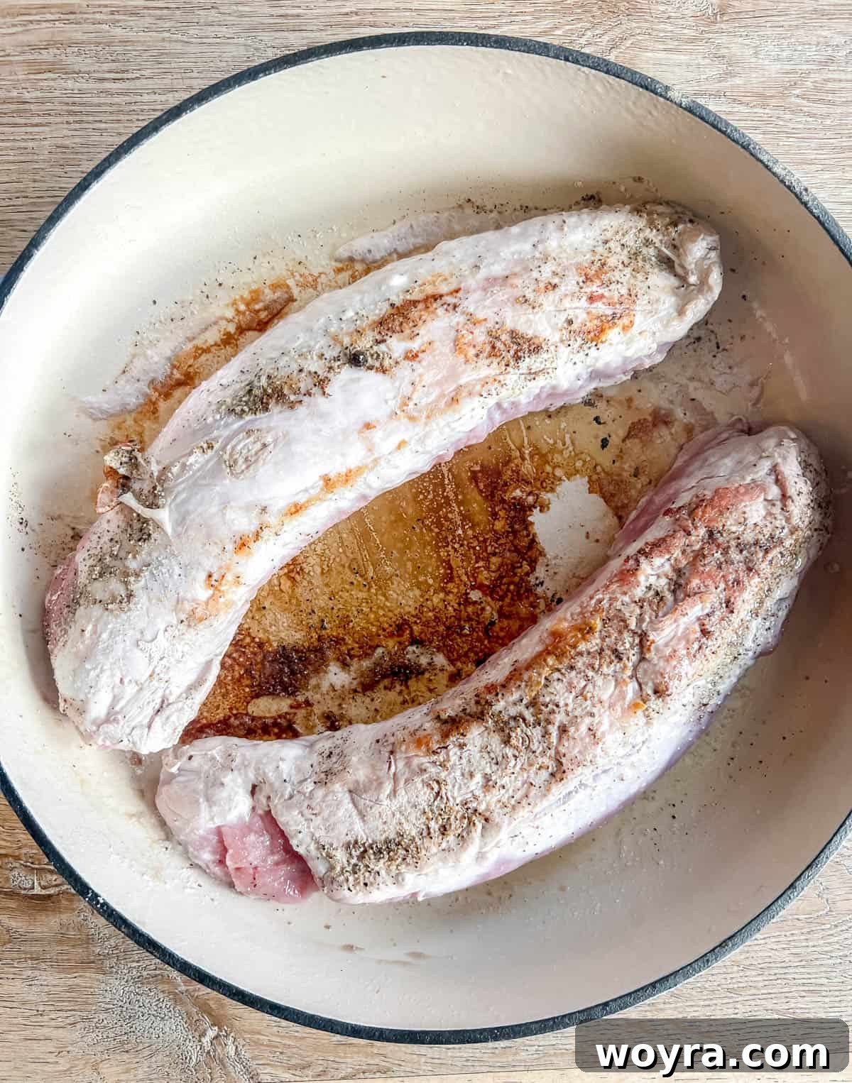 Dutch Oven Pork Tenderloin with Spiced Apples and Figs 4 Perfectly seared pork tenderloin, golden brown on all sides, resting on a plate, ready for the next step of cooking. The dark, caramelized crust indicates rich flavor development.