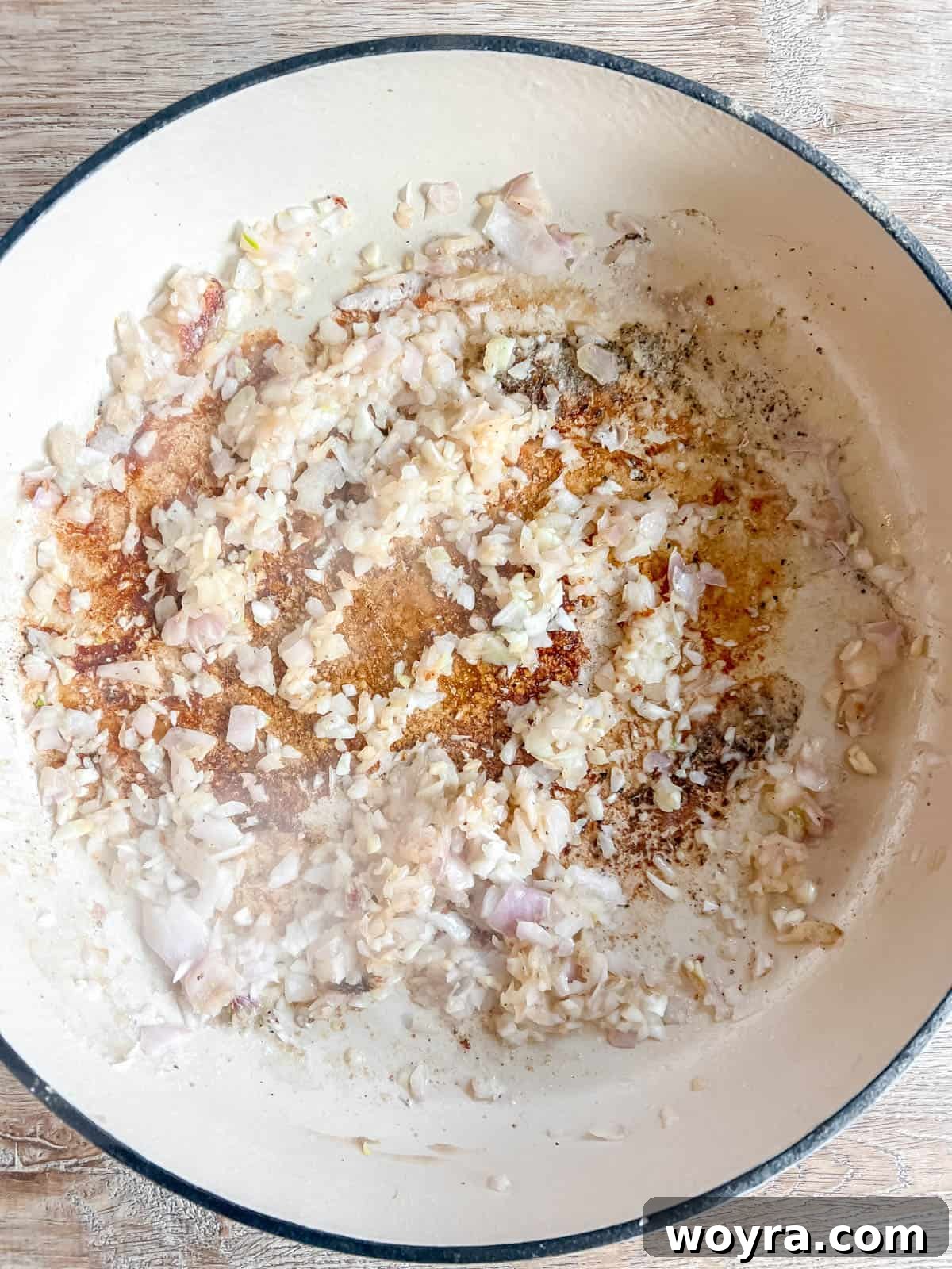 Dutch Oven Pork Tenderloin with Spiced Apples and Figs 5 Minced shallots and garlic sizzling gently in a Dutch oven with a bit of olive oil, becoming translucent and fragrant. The bottom of the pan shows some browned bits from the previous searing step, adding depth.