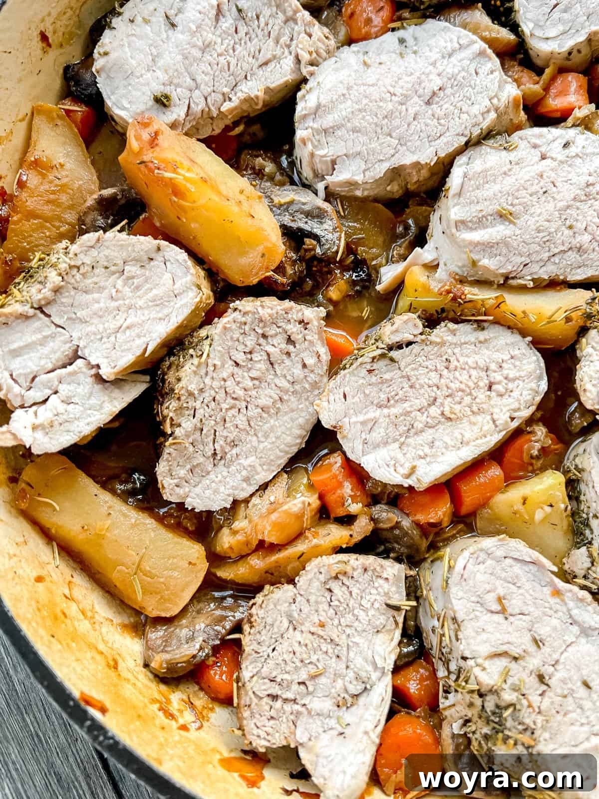 Dutch Oven Pork Tenderloin with Spiced Apples and Figs 9 A close-up view of the delicious fig pork tenderloin dish in a Dutch oven, showcasing its rich colors and tender texture. The sliced pork is visibly juicy, surrounded by caramelized apples and figs, with herbs sprinkled throughout.