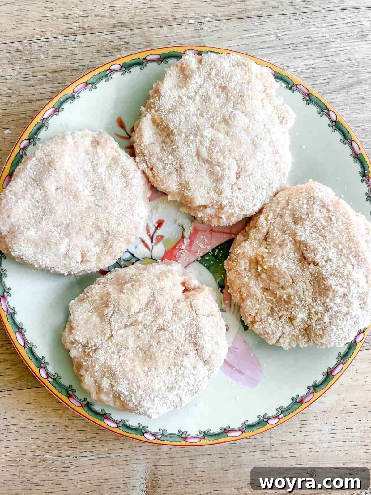 Uncooked chicken burgers resting on a plate.