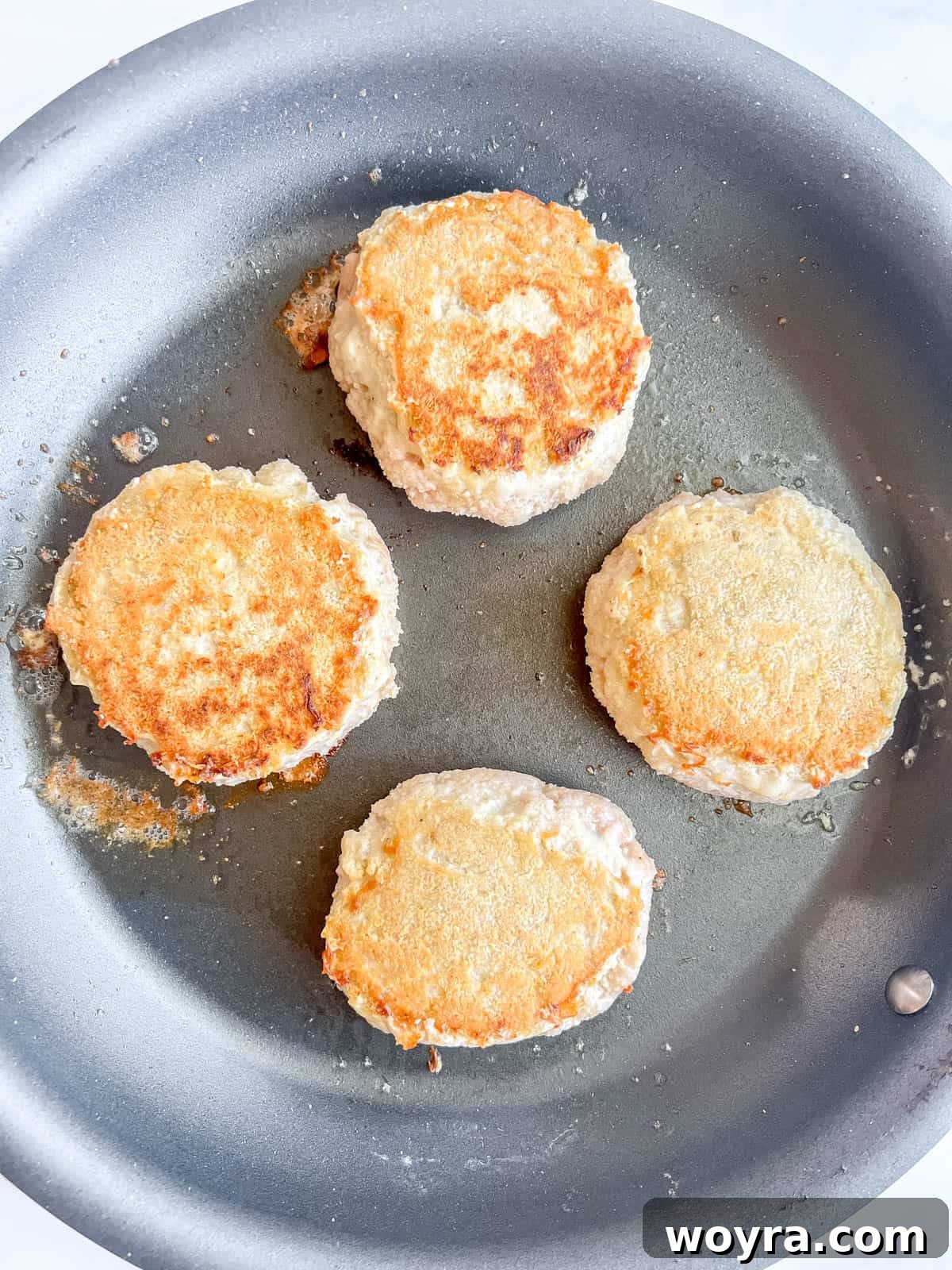 Chicken burgers flipped, showing a golden brown crust.