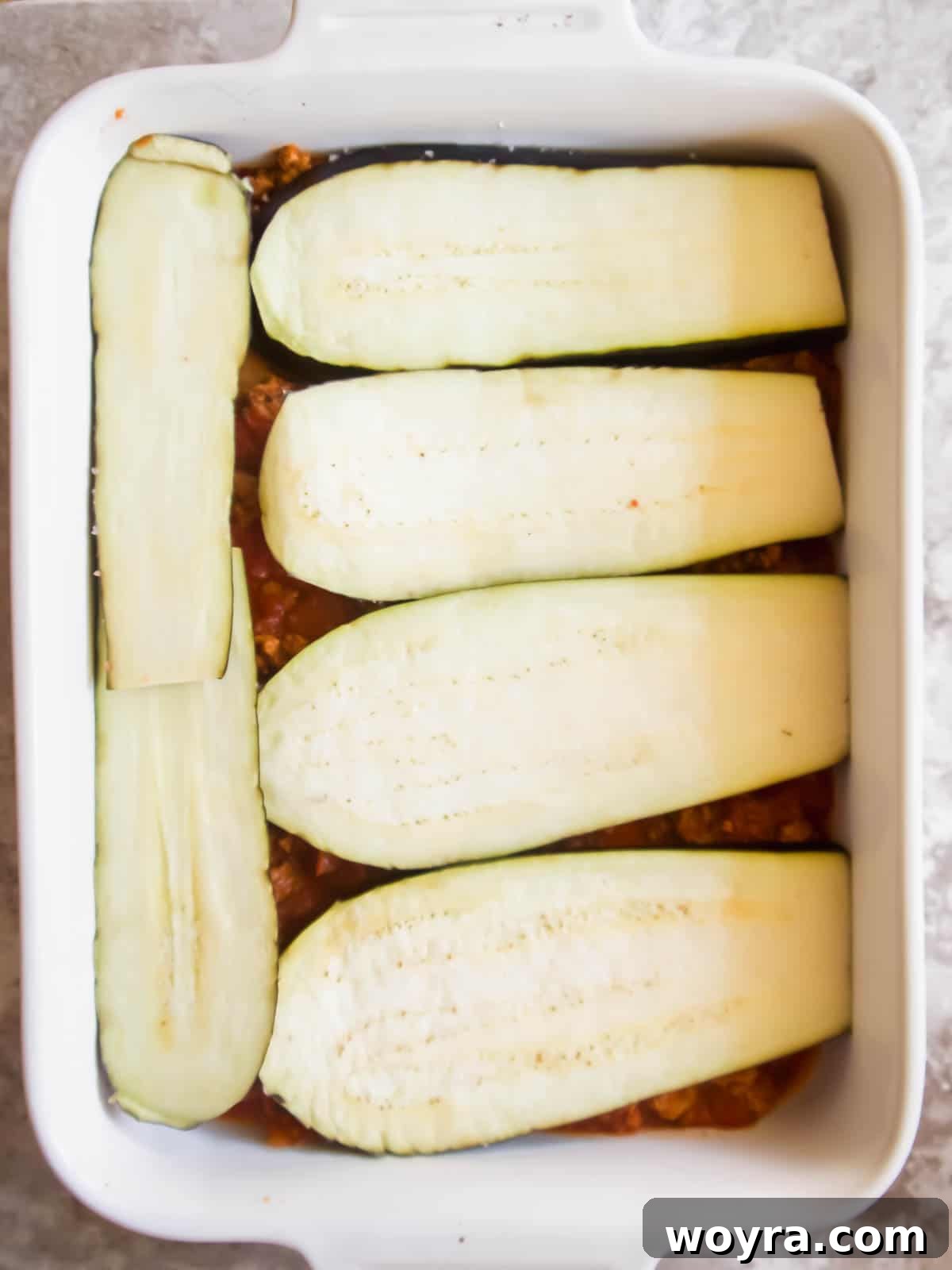 Summer Harvest Turkey Casserole 6 The first layer of prepared eggplant slices carefully placed over the meat sauce in the baking pan.