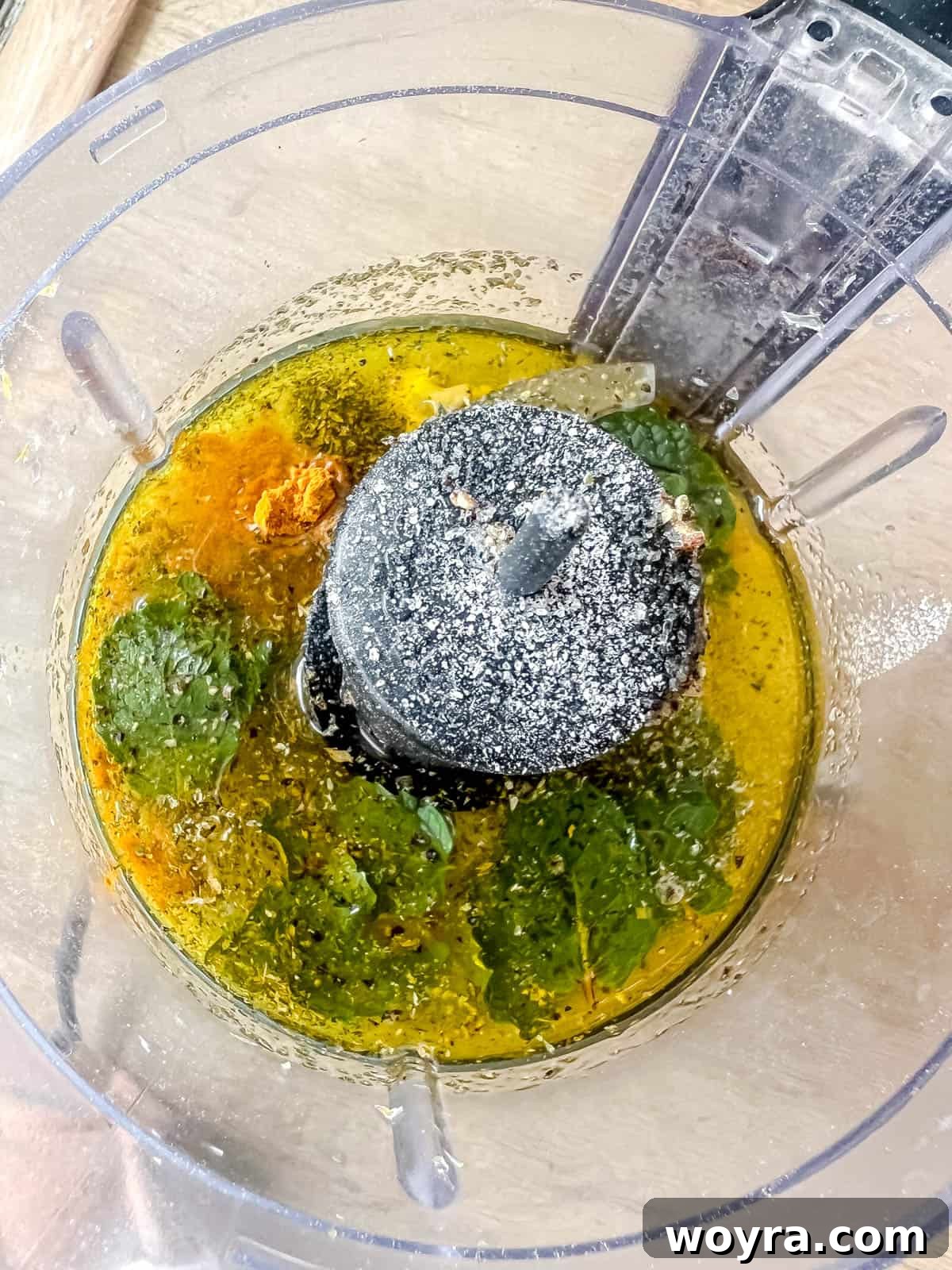 Golden Lemon Turmeric Mint Dressing 4 All the lemon mint dressing ingredients, including fresh mint leaves, lemon juice, olive oil, and turmeric, placed inside a food processor bowl.