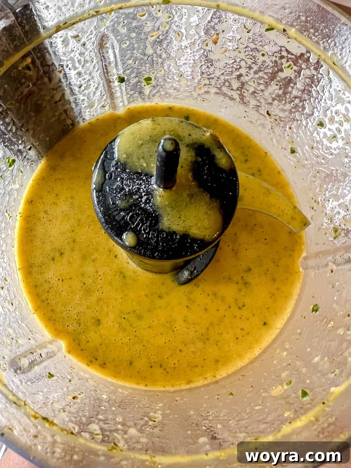 Golden Lemon Turmeric Mint Dressing 5 The blended lemon turmeric dressing with mint, showing a smooth, vibrant yellow consistency in the food processor.