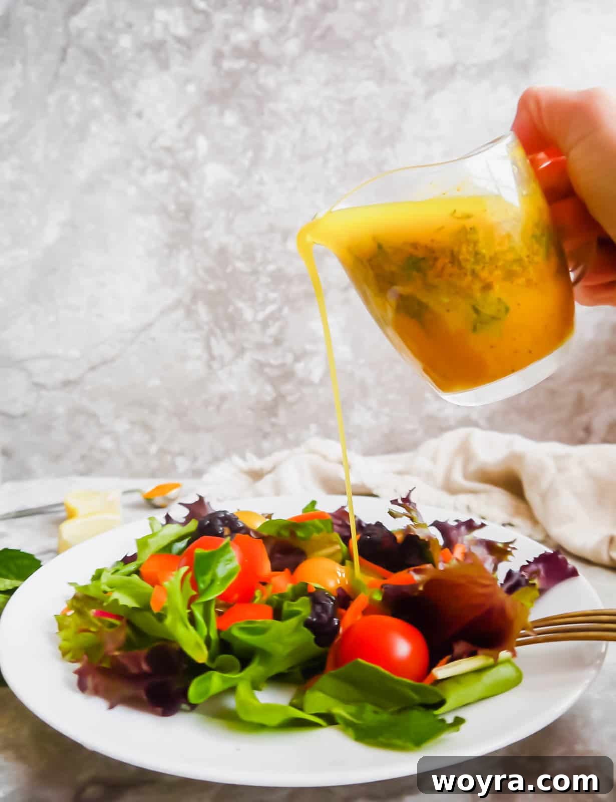 Golden Lemon Turmeric Mint Dressing 6 The vibrant lemon turmeric dressing with mint being generously poured over a fresh, colorful salad, making it look irresistible.