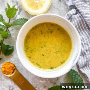 Lemon Turmeric dressing in a bowl surrounded by mint and turmeric.