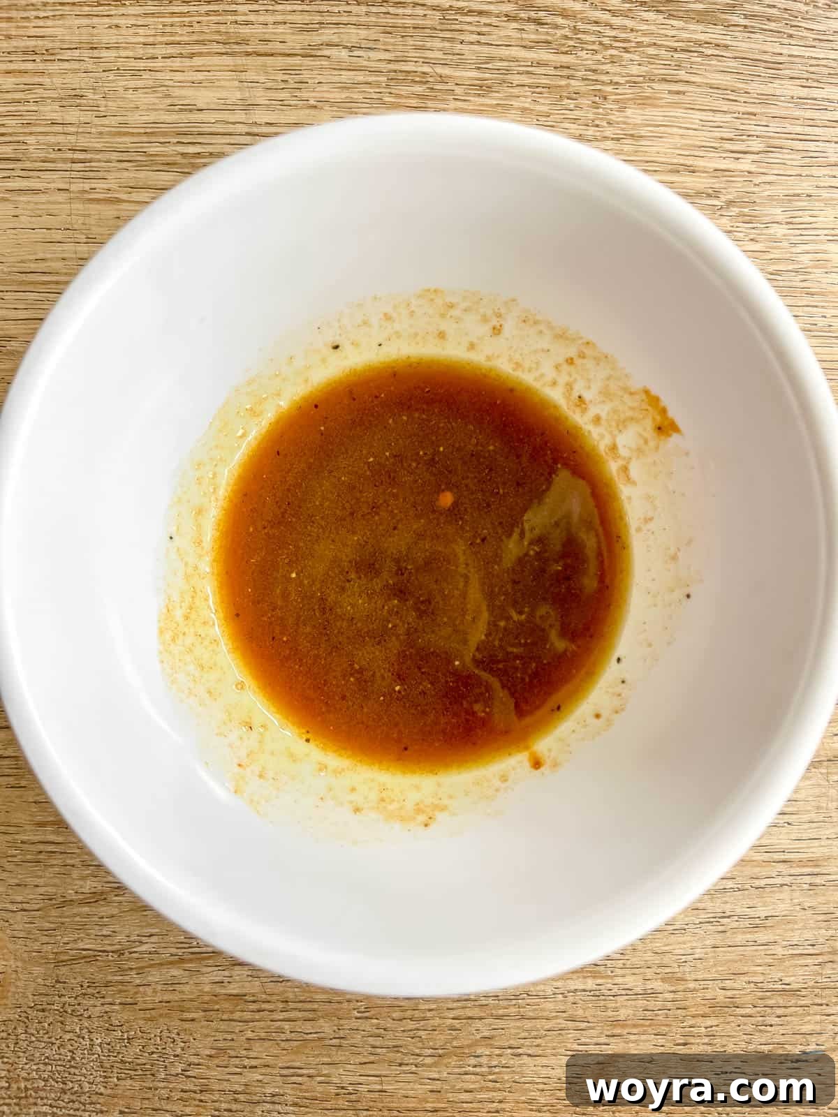 Mixing olive oil, maple syrup, turmeric, salt, and pepper in a small bowl to create the glaze.