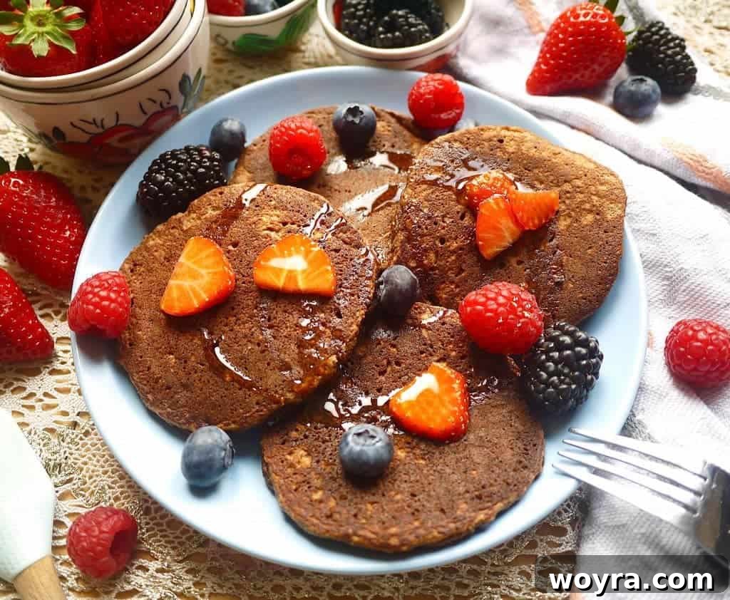 Decadent Paleo Chocolate Pancakes 3 Close-up of fluffy Chocolatey Cocoa Paleo Pancakes topped with fresh berries, showcasing their delicious texture
