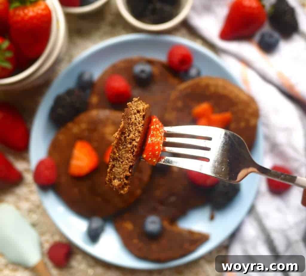 Decadent Paleo Chocolate Pancakes 4 Stack of Chocolatey Cocoa Paleo Pancakes drizzled with maple syrup and topped with fresh berries and a sprinkle of cocoa powder
