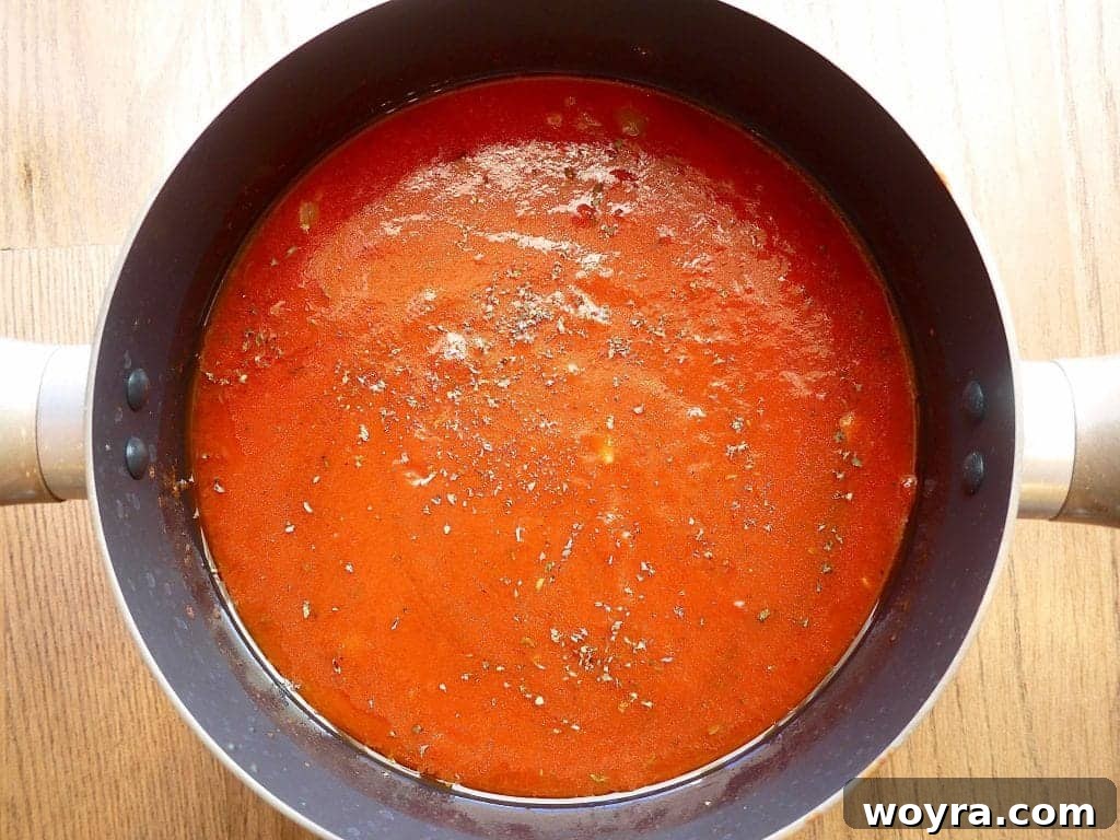Savory Almond Flour Meatballs with Rich Sauce 6 Marinara sauce ingredients, including tomatoes, herbs, and spices, added to a pot before simmering.