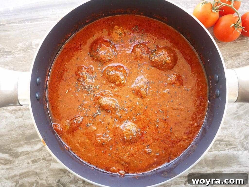 Savory Almond Flour Meatballs with Rich Sauce 8 Cooked gluten-free meatballs simmering in a rich, dark red marinara sauce after three hours.