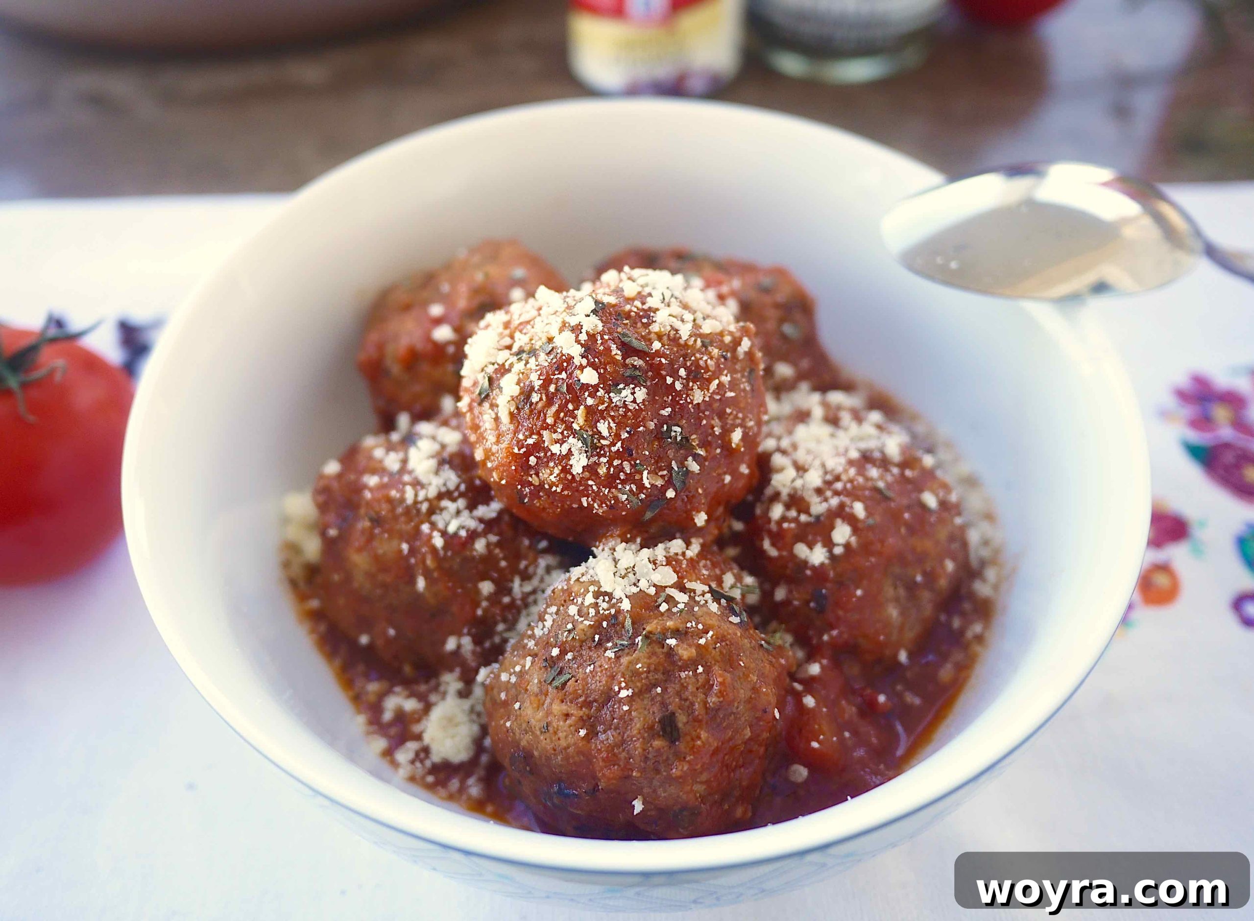 Savory Almond Flour Meatballs with Rich Sauce 9 A bowl of almond flour meatballs and sauce, generously topped with grated Parmesan cheese and fresh herbs.