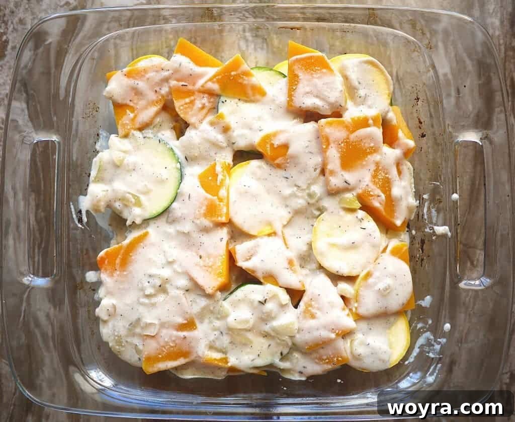 Paleo Friendly Squash Au Gratin 7 Creamy sauce being spread over a layer of squash in a casserole dish.