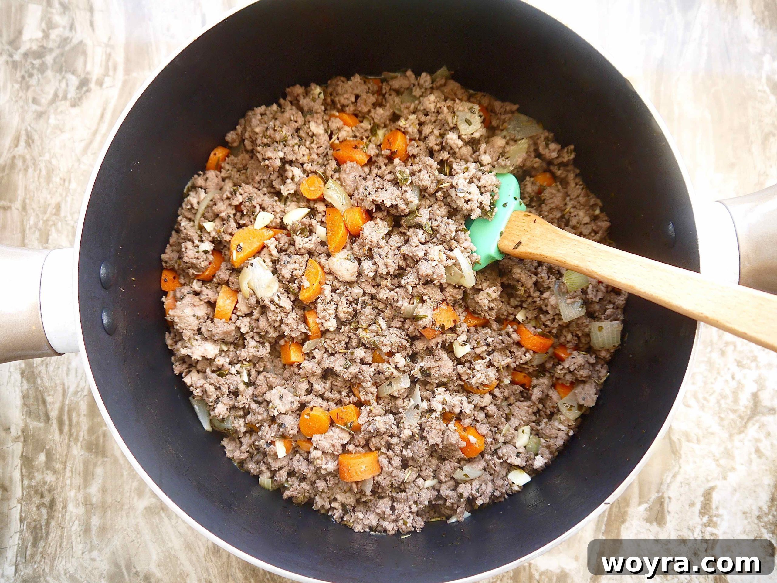 Golden Pumpkin Ragu 4 Close-up of browned ground beef and pork in a large pot, infused with herbs and aromatics, forming the base of the bolognese.