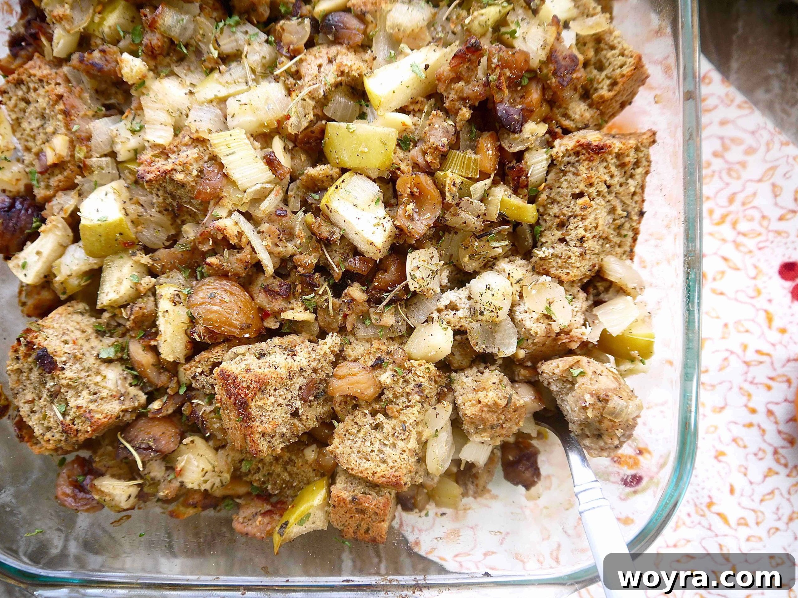 A large baking pan filled with golden-brown Paleo stuffing featuring sausage, apple, and chestnut pieces, ready to be served.