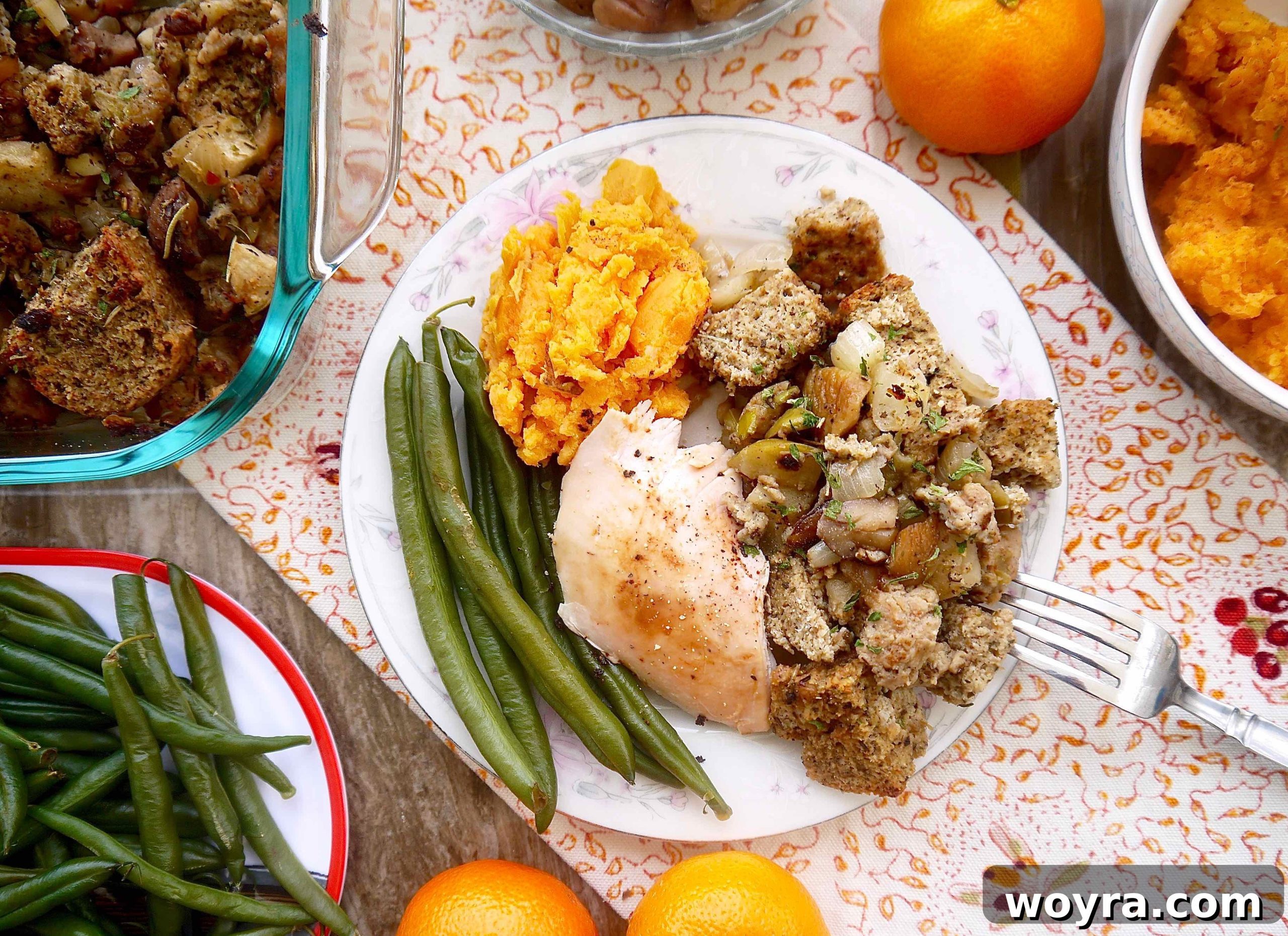 A plate featuring a generous serving of Paleo sausage stuffing alongside roasted turkey, creamy mashed potatoes, and vibrant green beans.