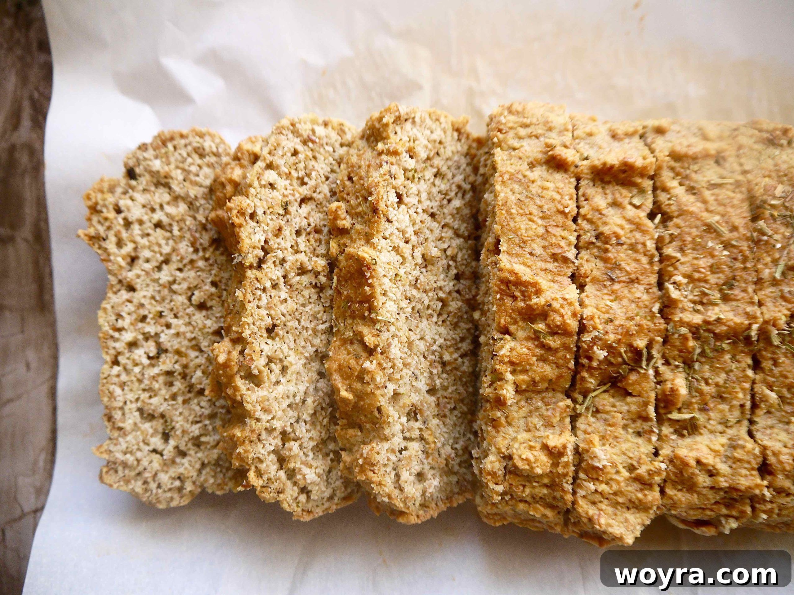 A freshly baked loaf of homemade flaxseed bread resting on a cooling rack, perfectly golden brown and ready to be cubed.