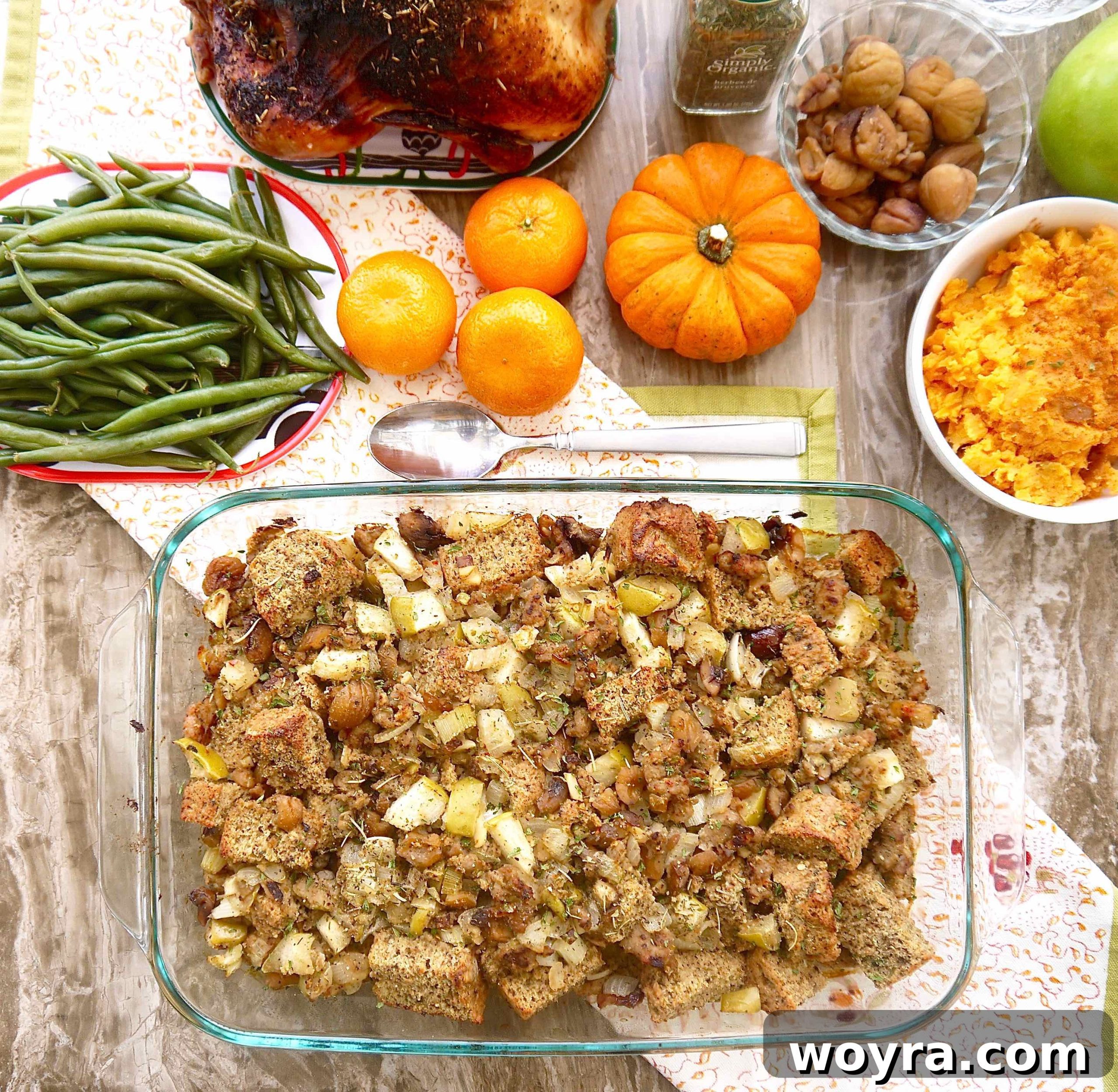 A festive holiday spread featuring a large pan of gluten-free chestnut stuffing with sausage, surrounded by other delicious side dishes.