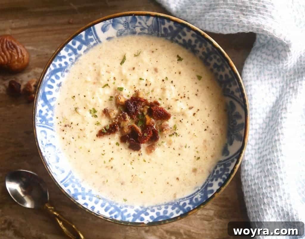 Primal Bacon Chestnut Cauliflower Soup 4 A bowl of creamy Paleo Cauliflower, Bacon, and Chestnut Soup, garnished with a sprig of rosemary and cracked black pepper, ready to be enjoyed.