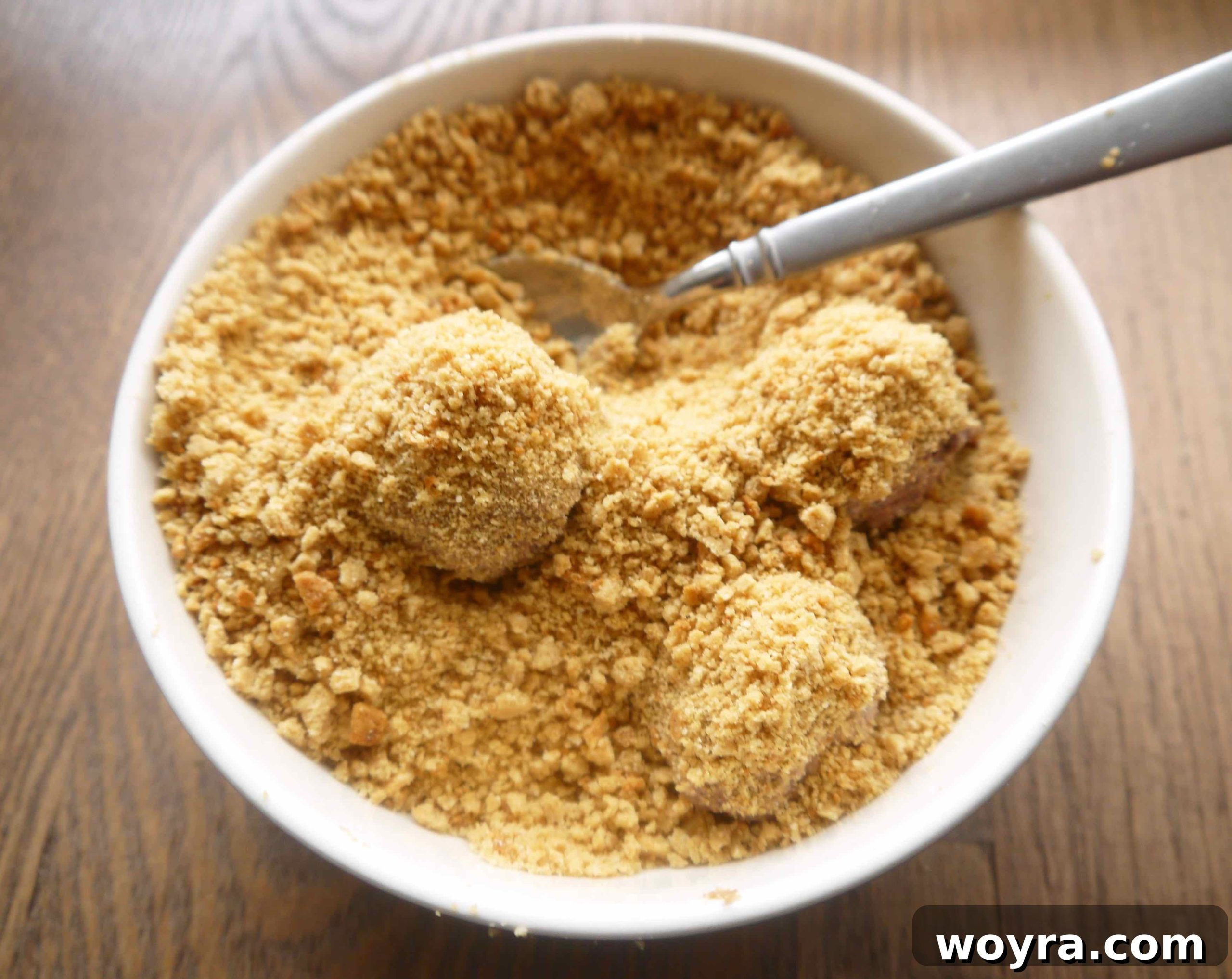Decadent Paleo Chocolate Mousse Truffles 11 A spoonful of firm Paleo chocolate mousse being carefully placed into a bowl of cookie crumbs, ready to be coated.