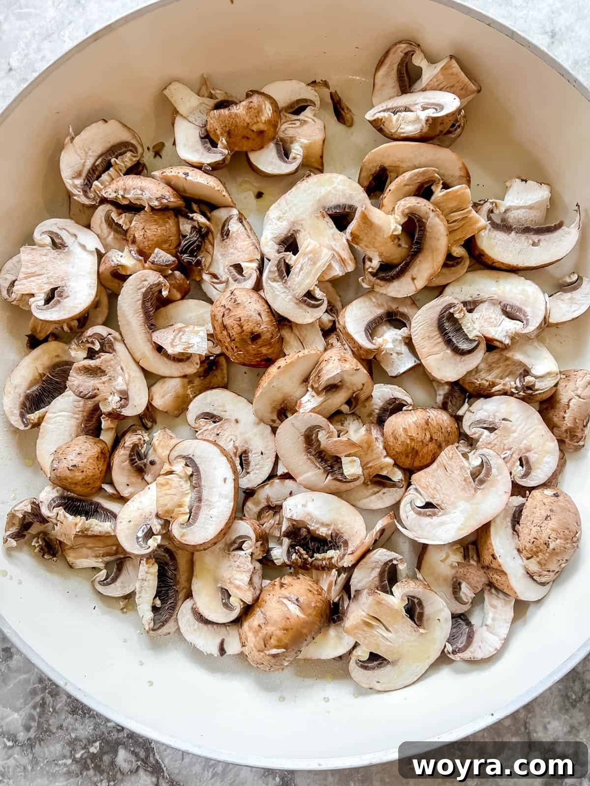Creamy Vegan Paleo Mushroom Sauce 4 Sliced baby bella mushrooms added to a hot frying pan with olive oil.