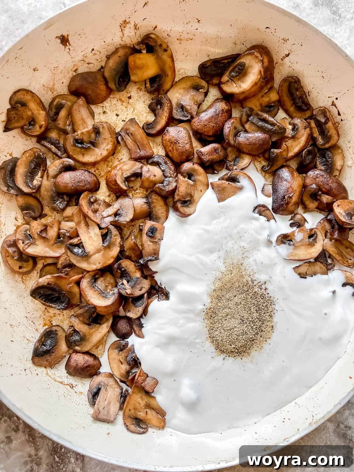 Creamy Vegan Paleo Mushroom Sauce 6 Coconut cream, black pepper, and salt added to cooked, browned mushrooms in a pan.