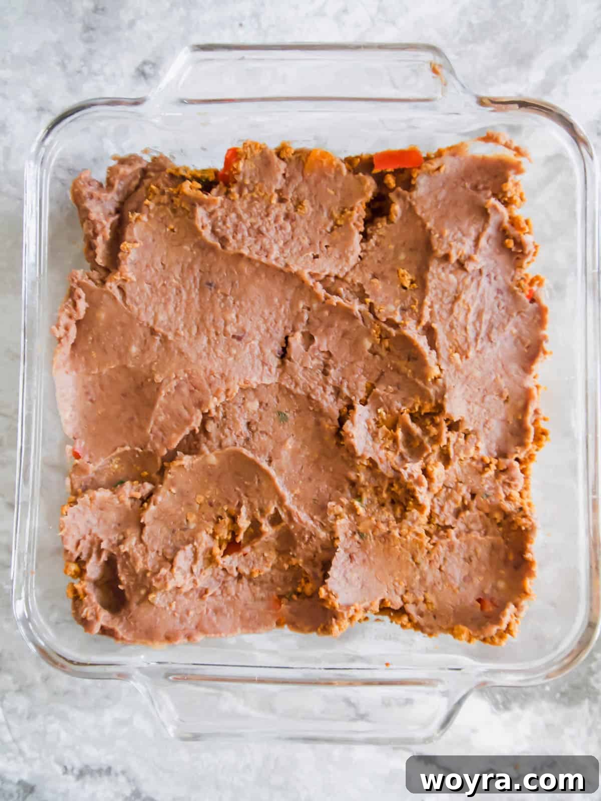 Ultimate Dairy-Free 7 Layer Turkey Taco Dip 8 Refried bean layer added on top of the ground turkey in the pan.