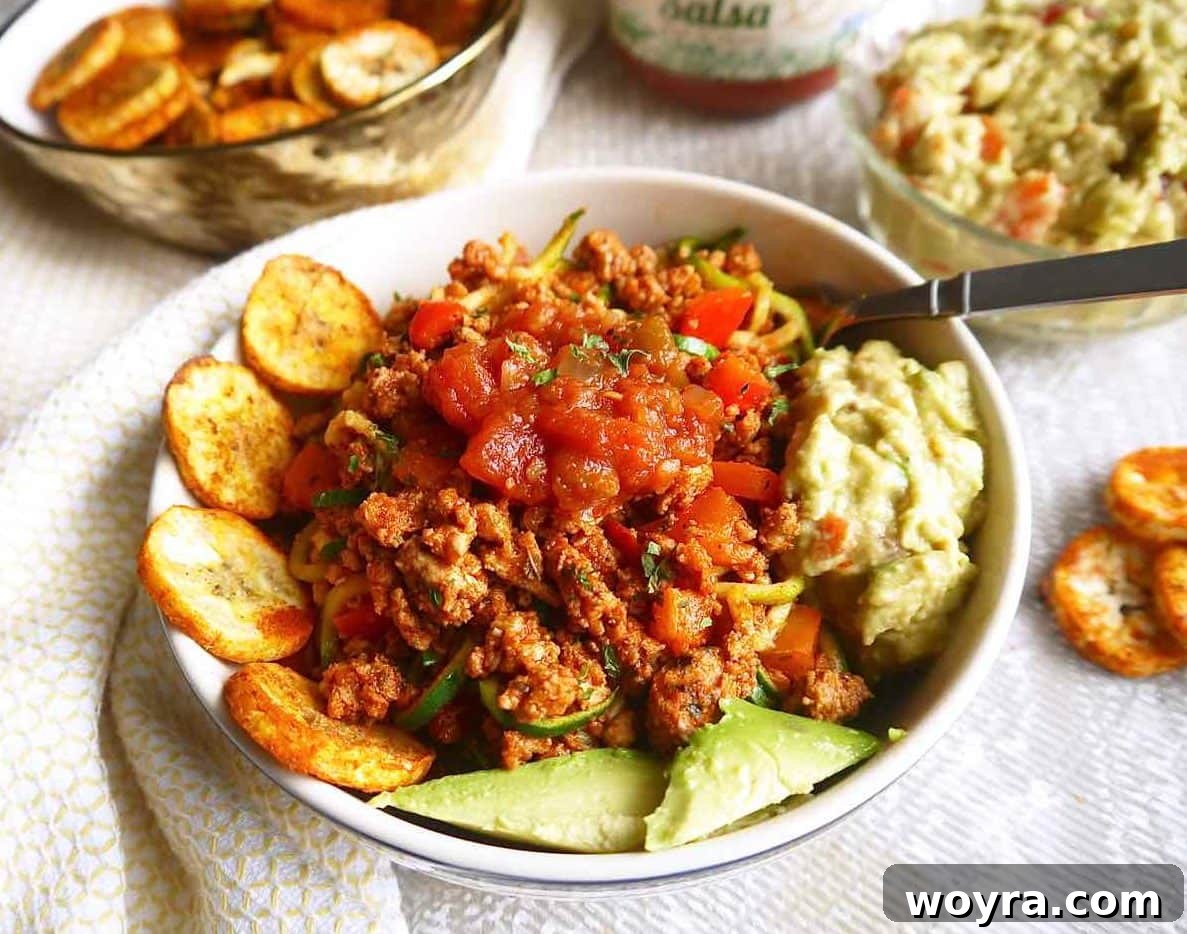 A vibrant taco bowl featuring ground turkey, zucchini noodles, and a variety of fresh taco toppings.