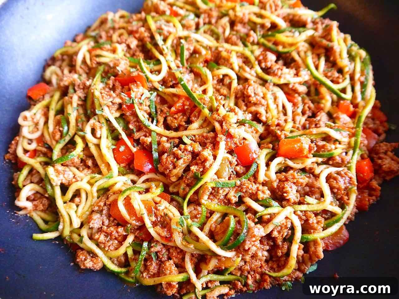 Combining the cooked taco meat with the zucchini noodles.