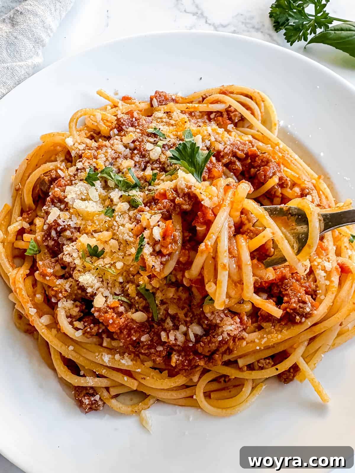 Meaty Slow Cooker Spaghetti Sauce 11 Spaghetti covered in slow cooker spaghetti sauce with ground beef, garnished with herbs.